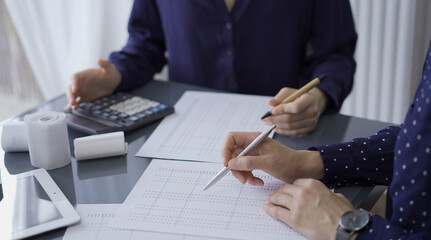 Obraz premium Two unrecognizable female accountants or auditors are sitting and reviewing financial documents in office. Audit and taxes
