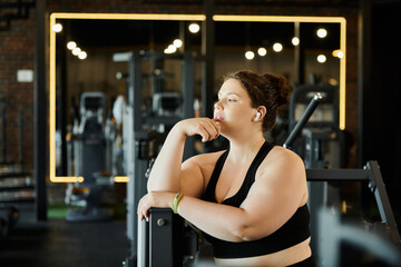 Fototapeta premium A plus-size woman embraces her strength and positivity during a workout session at the gym.