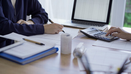 Accountants or auditors reviewing financial documents while sitting opposite one another at the wooden desk in office. Audit and taxes