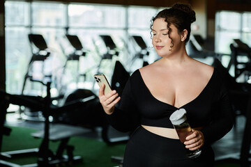 A young woman embraces body positivity as she works out in active wear, checking her phone.