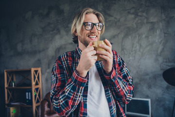 Portrait of young blond hair business man cheerful project manager holding cup tea indoors loft design modern office relaxed looking thoughtful