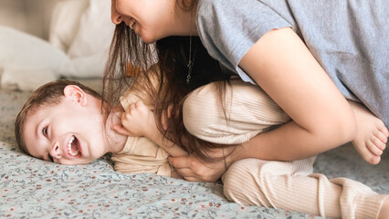 Mom tickles the feet of her little son, wrapped in a blue blanket. Mom and child have fun together...