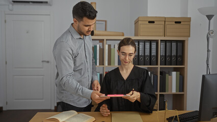 Man showing document to woman judge in office surrounded by law books and files suggesting a legal...