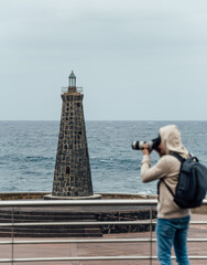 Tourist taking photos of a lighthouse on a cloudy day