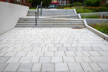 Fototapeta premium Tiled pedestrian pathway with steps within urban surroundings