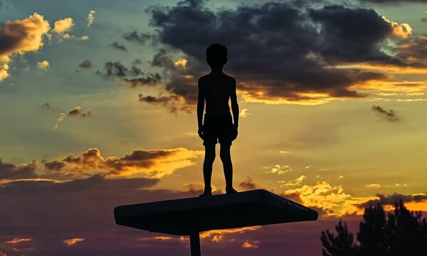 Silhouette of a Boy on a Diving Board at Sunset