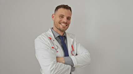 Confident young man in doctor coat and stethoscope smiling against a white background