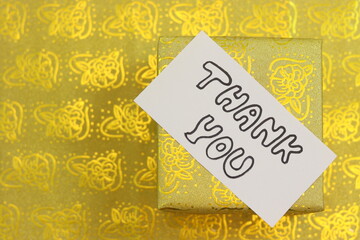 Thank you hand written notes with golden gift box in background.