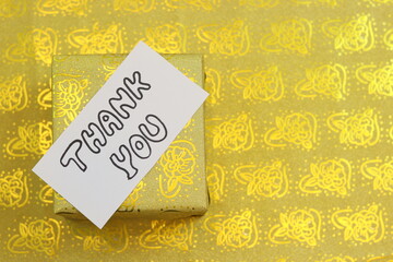 Thank you hand written notes with golden gift box in background.