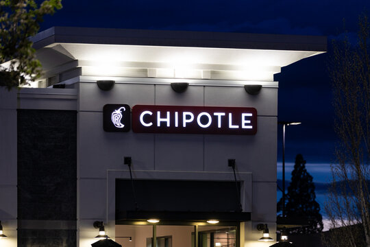 Beaverton, OR, USA - April 2, 2024 - Chipotle Mexican fast food chain restaurant with its big glowing illuminated logo at night. high quality picture for download