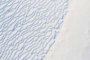 Beautiful winter background with snowy ground. Natural snow texture. Wind sculpted patterns on snow surface.