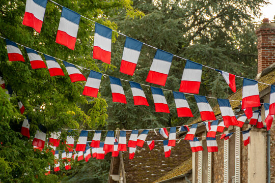 Arrangements de guirlandes de drapeaux tricolores d&eacute;corant la rue d'un village en France avec des arbres &agrave; l'arri&egrave;re plan. Concepts de f&ecirc;te nationale et d'&eacute;v&egrave;nement festif ou patriotique fran&ccedil;ais
