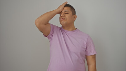 A stressed young hispanic man wearing a lavender shirt stands against an isolated white background, exuding a sense of concern.