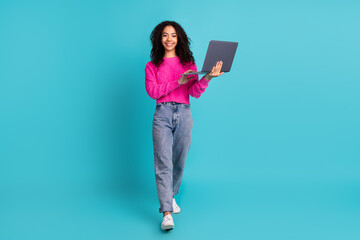 Full length photo of lovely teen lady hold netbook walk dressed stylish pink garment isolated on cyan color background