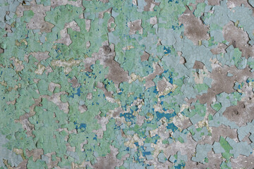 Peeling paint on the wall. Old concrete wall with cracked flaking paint. Weathered rough painted surface with patterns of cracks and peeling. Grunge texture for background and design. High resolution.