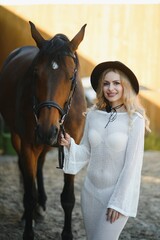 Obraz premium Beautiful model girl stands in a long dress with a horse