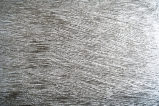 A silver textured surface with a soft, brushed finish, showcasing fine, parallel lines that add a soft, linear texture.