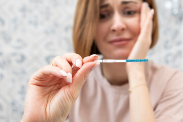 Portrait of stressing woman sits in the lavatory and holds pregnancy test in her hand