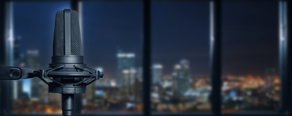 podcast microphone in a modern building interior with the lights of a big city at night in the background