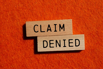 Claim denied message written on wooden blocks with orange background. Conceptual claim denied...