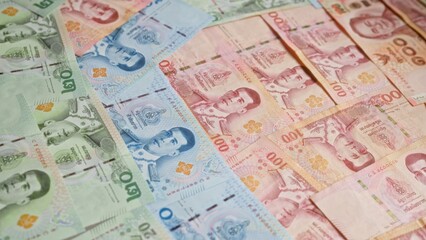 Variety of colorful thai baht banknotes spread out, showcasing multiple denominations from thailand.