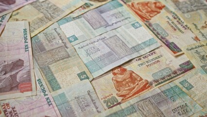 Egyptian banknotes spread out showing various denominations including five, ten, and two hundred pounds with vibrant designs and intricate patterns.