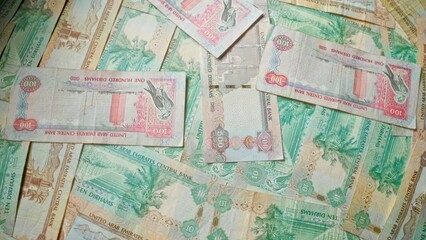 Fototapeta premium Scattered uae banknotes including ten and one hundred dirhams showcasing colorful designs from the united arab emirates central bank
