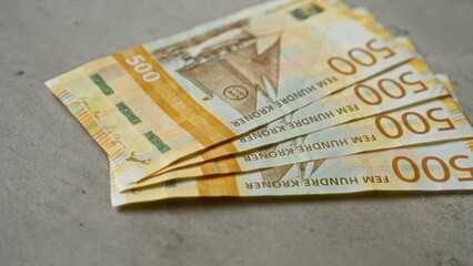 Norwegian banknotes featuring 500 kroner denominations displayed on a concrete surface, showcasing...