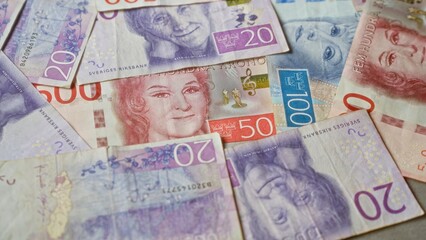 Swedish krona banknotes scattered across a surface, showcasing various denominations and colorful designs from sweden's currency.