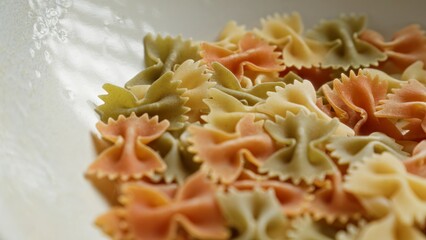 Closeup of colorful bow tie pasta in a white bowl, showcasing vibrant food textures and fresh ingredients