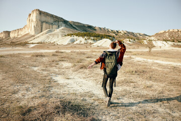 solitary hiker trekking through vast field towards majestic mountain backdrop