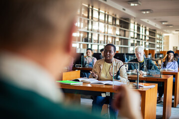 Female student talking to professor during a lecture in a university library