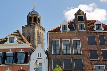 Traditional historic medieval houses, located on the banks of the river Ijssel, in the historical city center of Deventer, Overijssel, Netherlands, with the bell tower of Lebuinus church
