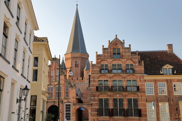 Obraz premium Traditional historic medieval houses in the old picturesque town of Zutphen, Gelderland, Netherlands, with Drogenapstoren tower (ancient gateway to the city) in the background