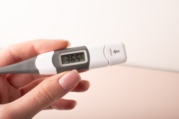 Womans hand holding thermometer that shows normal human temperature. Measuring body temperature. Health check. Health care concept. High quality photo