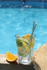 Tasty cocktail in glass near swimming pool outdoors