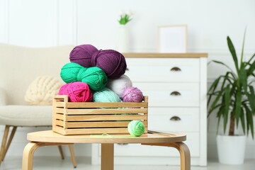 Wooden crate with different yarns on coffee table indoors