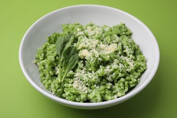 Delicious spinach risotto with parmesan cheese on light green background, closeup