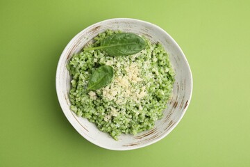 Tasty spinach risotto on light green background, top view
