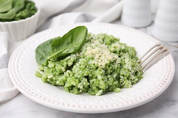 Tasty spinach risotto served on white marble table, closeup