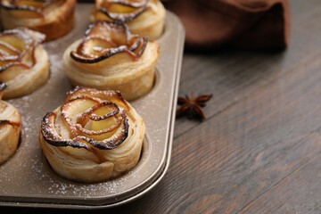 Puff pastry. Freshly baked apple roses on wooden table, closeup. Space for text