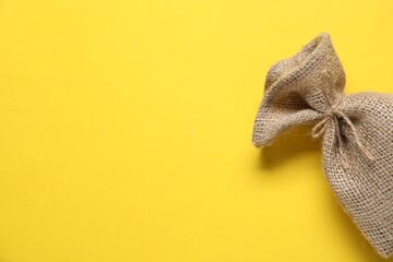 One burlap sack on yellow background, top view. Space for text