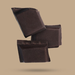 Pieces of sweet chocolate falling on color background