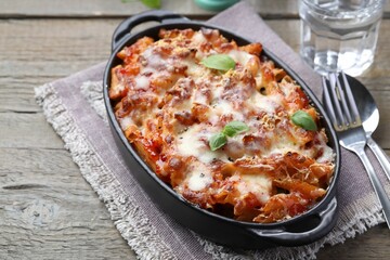 Delicious al forno pasta in baking dish on wooden table, closeup