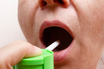 person using mouth spray to cure the throat