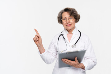 Portrait of smiling mature senior woman, female doctor wearing white coat uniform, stethoscope, looking at camera holding clipboard isolated on white background. Health care concept