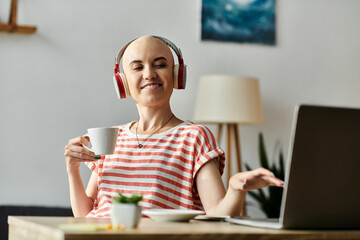 A cheerful bald woman sits at her desk, sipping coffee and listening to music on her headphones.