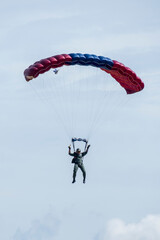 A man flies with parachute on blue sky background