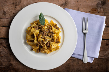 Plate with pappardelle with wild boar ragout sauce with bay leaf and napkin