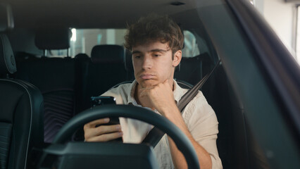 Caucasian confused sad driver upset puzzled male businessman frustrated man stressed business employer in car auto automobile parking lot traffic jam gadget addict lost problem bad news mobile phone © Yuliia